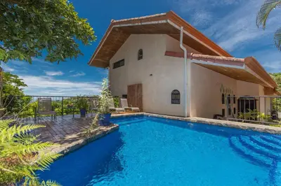 a villa with a swimming pool in front of a house at Casa Sophia A Cozy, Treetop, Sea View Gem in Quepos