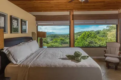 a bedroom with a bed and a large window at Casa Sophia A Cozy, Treetop, Sea View Gem in Quepos