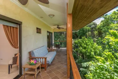 an open porch with a couch and a table at Casa Sophia A Cozy, Treetop, Sea View Gem in Quepos