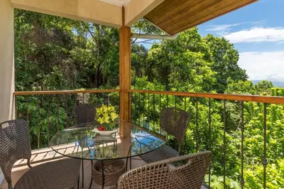 an outdoor patio with a glass table and chairs at Casa Sophia A Cozy, Treetop, Sea View Gem in Quepos