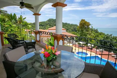 a balcony with a glass table with flowers on it at Shana Residences 310 Sea View Condo Walk to beach in Manuel Antonio