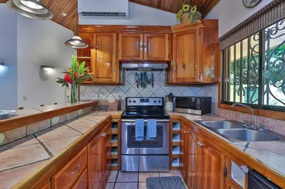 a kitchen with wooden cabinets and a stove top oven at Alma Pacifica, Charming, secure and lots of wildlife in Manuel Antonio