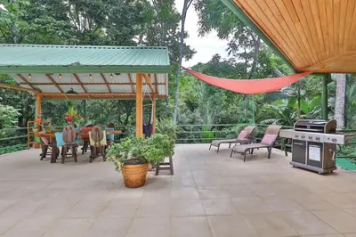 a patio with a grill and tables and chairs at Alma Pacifica, Charming, secure and lots of wildlife in Manuel Antonio