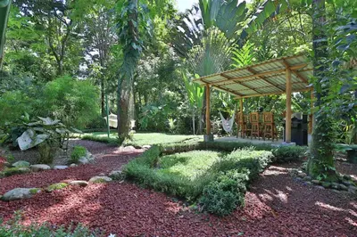 a garden with a wooden pergola and a bench at Alma Pacifica, Charming, secure and lots of wildlife in Manuel Antonio