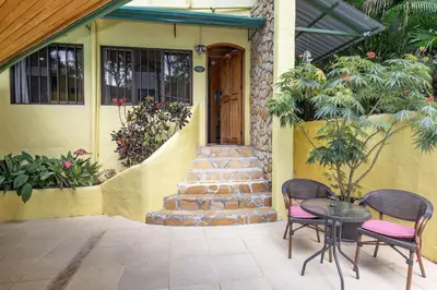 a house with two chairs and a table in front of a door at El Gekko spacious studio in Manuel Antonio