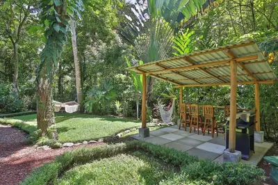 a wooden pavilion with chairs and a table in a garden at El Gekko spacious studio in Manuel Antonio