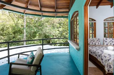 a room with a bed and a chair on a balcony at Casa Pura Vida Manuel Antonio in Manuel Antonio