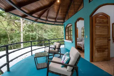 a porch of a house with chairs and a table at Casa Pura Vida Manuel Antonio in Manuel Antonio