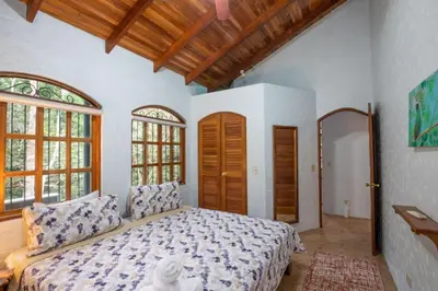 a bedroom with a bed and two windows at Casa Pura Vida Manuel Antonio in Manuel Antonio