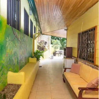 a living room with a yellow couch in a building at Dos Palmas1200sqft 1King 1Queen,AC,WiFi,Pool,Gated in Manuel Antonio