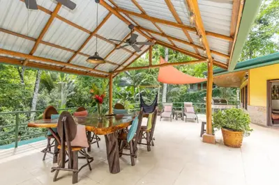 a patio with a wooden table and chairs under a pergola at Dos Palmas1200sqft 1King 1Queen,AC,WiFi,Pool,Gated in Manuel Antonio