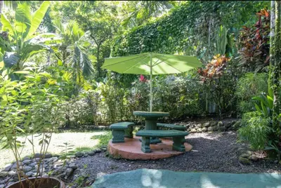 a green picnic table with an umbrella in a garden at Dos Palmas1200sqft 1King 1Queen,AC,WiFi,Pool,Gated in Manuel Antonio