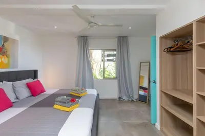 a bedroom with a large bed with red and yellow pillows at La Maison Blanche Nicoya, Pool, Views, and Wildlife in Manuel Antonio