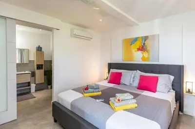 a bedroom with a large bed with colorful pillows on it at La Maison Blanche Nicoya, Pool, Views, and Wildlife in Manuel Antonio