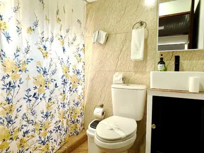 a bathroom with a toilet and a floral shower curtain at Casa Blanca Manuel Antonio B3, Central, Pool, Gated in Quepos