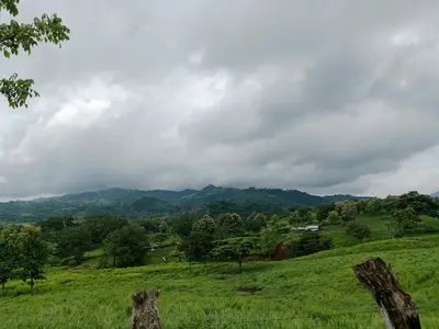 a green field with mountains in the background at Pacific villa lisn in Nicoya