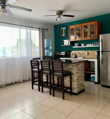 a kitchen with a counter with chairs and a refrigerator at Bejuco House in Parrita