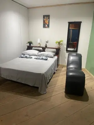 a bedroom with a bed and a black leather chair at Cabaña El Mirador de las Montañas in Turrialba