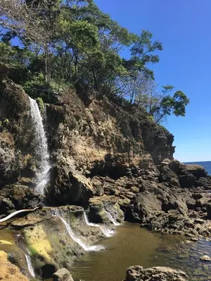 a waterfall on a rocky hill next to the ocean at Villa Carpintera in Puntarenas