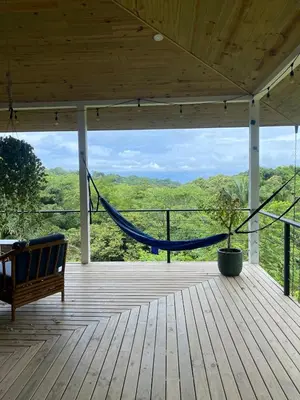 a hammock on a deck with a view of the mountains at Jungle Beach House in Uvita