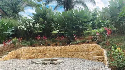 a stone retaining wall in a garden with plants at Jungle Beach House in Uvita