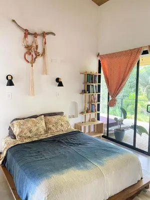 a bedroom with a bed and a large window at Jungle Beach House in Uvita