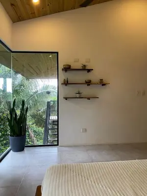 a bedroom with a bed and a large window at Jungle Beach House in Uvita