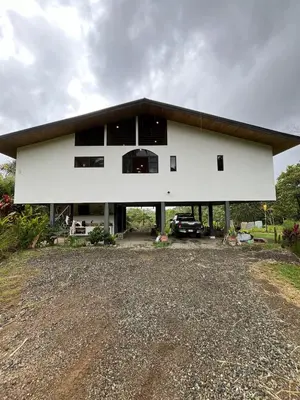 a white house with a car parked in front of it at Jungle Beach House in Uvita