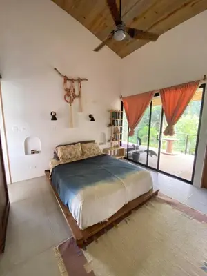 a bedroom with a bed and a large window at Jungle Beach House in Uvita