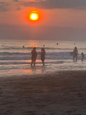 a group of people standing on the beach at sunset at JJ Lux Residential in Jacó