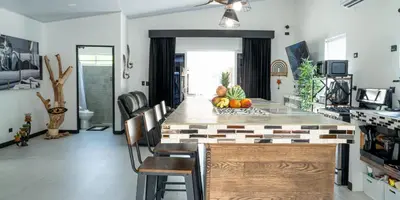 a kitchen with a counter with chairs and a table at JJ Lux Residential in Jacó