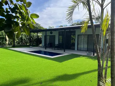 a house with a green yard with a swimming pool at Casa Flor in Playa Avellana