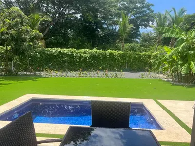 a backyard with a swimming pool and green grass at Casa Flor in Playa Avellana