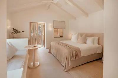 a white bedroom with a bed and a table at Hotel Fermata in Santa Teresa Beach