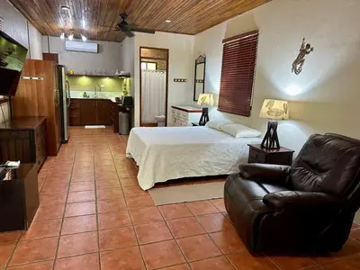 a bedroom with a bed and a couch and a kitchen at Jungle Creek, Casita Colibri, Studio with Big Patio in Quepos