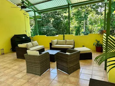 a patio with wicker chairs and tables on a yellow wall at Jungle Creek, Casita Colibri, Studio with Big Patio in Quepos