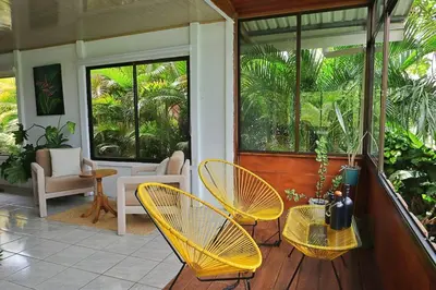 a porch with yellow chairs and a table and chairs at Volcano & Lake Arenal View Suite with Soaking tub in El Castillo de La Fortuna