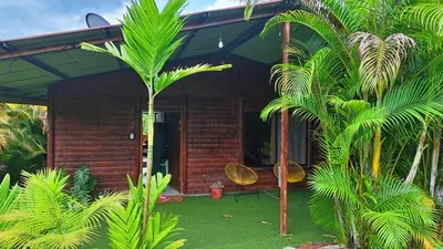 a house with palm trees in front of it at Volcano & Lake Arenal View Suite with Soaking tub in El Castillo de La Fortuna
