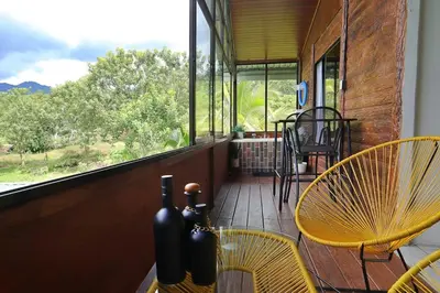 a porch with a table and chairs and a window at Volcano & Lake Arenal View Suite with Soaking tub in El Castillo de La Fortuna