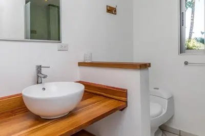a bathroom with a white sink and a toilet at Tortuga, 1BR Apartment in Villa Mar y Sol, Pool, Big Deck, and Wildlife in Manuel Antonio