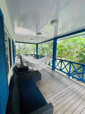 a porch with a hammock and chairs on a house at Costa Rica Beach Bungalow in Playa Hermosa