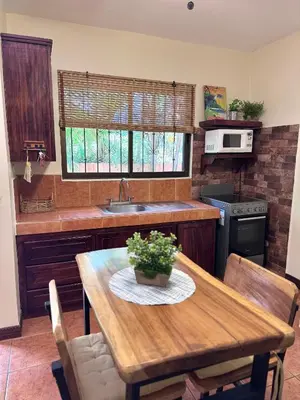 a kitchen with a wooden table and a sink at Tiny Paradise Ground Floor Studio in Coco