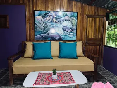 a couch with blue pillows and a table in a room at Peaceful Jungle Home, River Access, Arenal Views in El Castillo de La Fortuna