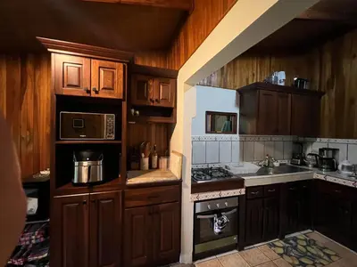 a kitchen with wooden cabinets and a stove top oven at Peaceful Jungle Home, River Access, Arenal Views in El Castillo de La Fortuna