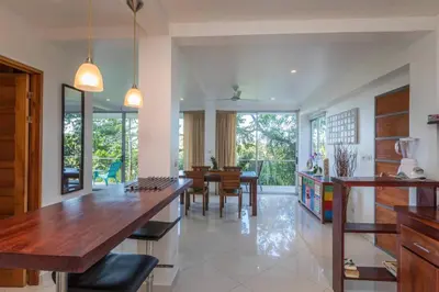 a kitchen and dining room with a table and chairs at Lapa Roja, 2BR Ocean View Apartment in Villa Mar y Sol, Nature in Manuel Antonio