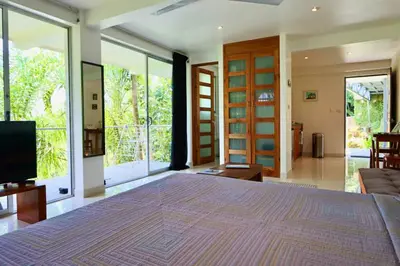 a bedroom with a large bed and large windows at Mariposa, 1BR Apart in Villa Mar y Sol, Pool, Balcony, and Wildlife in Manuel Antonio