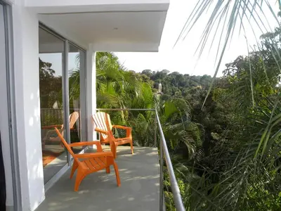 a porch with two chairs on a house at Mariposa, 1BR Apart in Villa Mar y Sol, Pool, Balcony, and Wildlife in Manuel Antonio