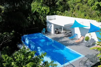 an overhead view of a swimming pool with blue umbrellas at Mariposa, 1BR Apart in Villa Mar y Sol, Pool, Balcony, and Wildlife in Manuel Antonio