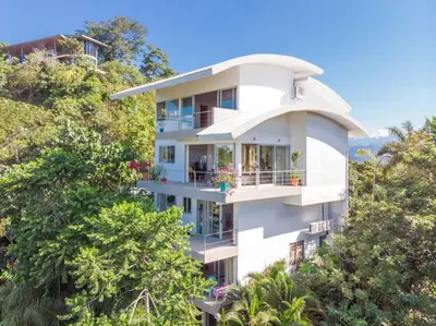 a white building on a hill with trees at Mariposa, 1BR Apart in Villa Mar y Sol, Pool, Balcony, and Wildlife in Manuel Antonio