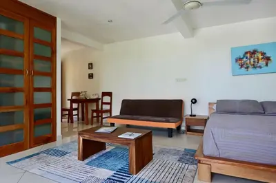 a bedroom with a bed and a couch and a table at Mariposa, 1BR Apart in Villa Mar y Sol, Pool, Balcony, and Wildlife in Manuel Antonio